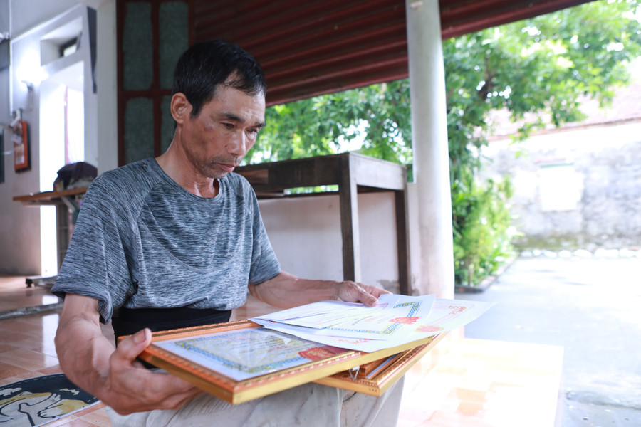 Ông Nguyễn Hữu Long - bố của Khiêm lưu giữ cẩn thận những tờ giấy khen của con trai trong nhiều năm qua. Ảnh: Đình Tuệ. 1.jpg